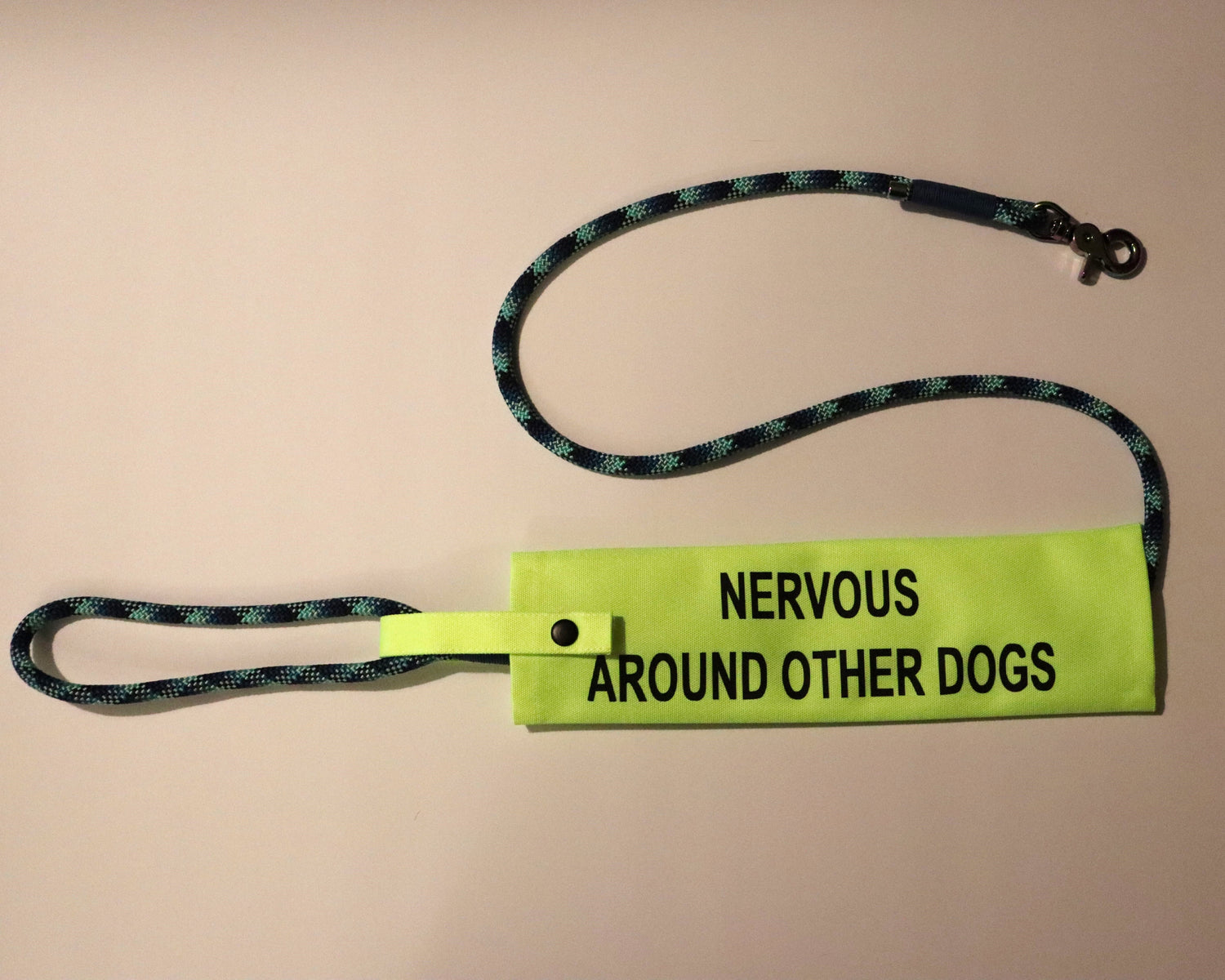 Bright yellow lead sleeve with bold black text, attached to a leash. Designed to clearly communicate messages to others during dog walks.